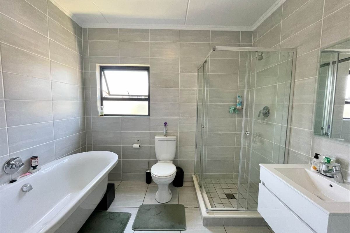 Modern bathroom featuring a freestanding bathtub, a separate glass-enclosed shower, a wall-mounted vanity, and neutral floor-to-ceiling tiling.