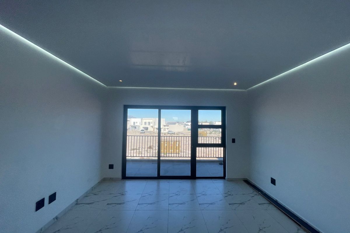 Modern living area featuring marble-look tiled flooring, recessed LED perimeter ceiling lighting, and large sliding glass doors leading to an outdoor balcony.
