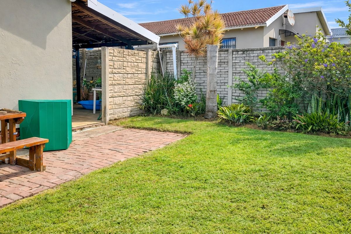 A private rear garden featuring a brick-paved patio area, a well-maintained lawn, and established perimeter walling.