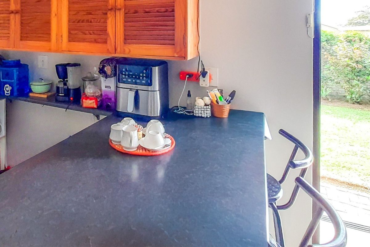 Kitchen area featuring a dark laminate countertop, wooden cabinetry, and direct access to the outdoor garden space.