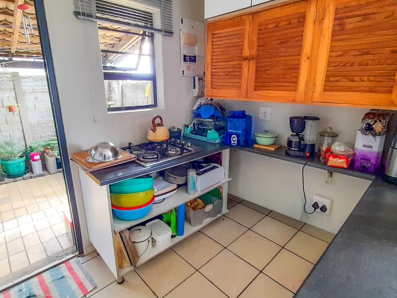 A compact kitchen area featuring wooden cabinetry, a built-in gas hob, and direct access to an outdoor patio space.