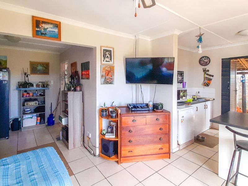 An open-plan living and kitchen area featuring tiled flooring, a breakfast counter, and direct access to an outdoor patio space.