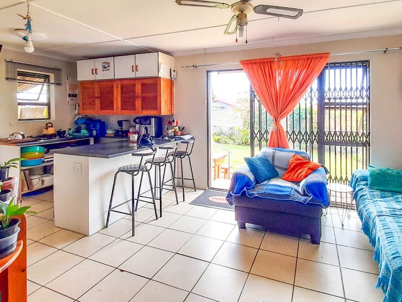 Open-plan living area featuring a kitchen with breakfast bar, tiled flooring, and sliding door access to the rear garden.