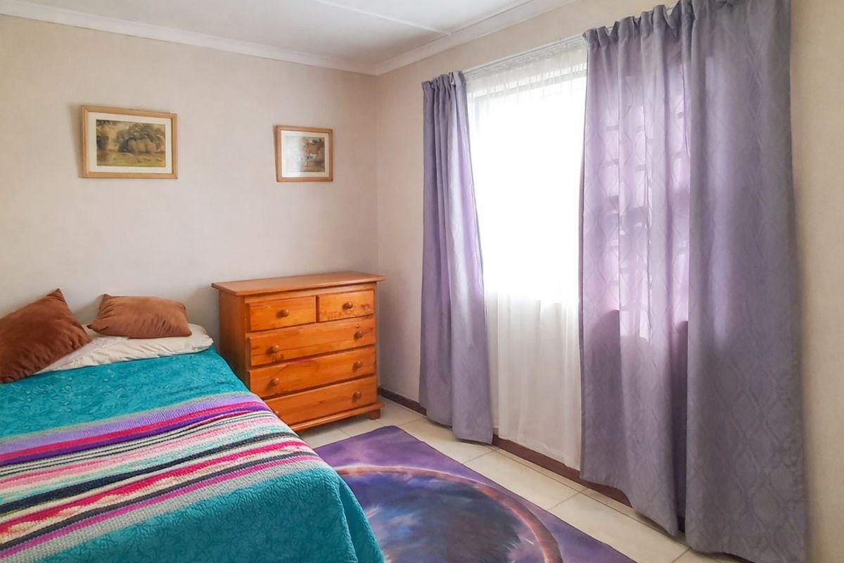 A standard bedroom featuring tiled flooring and a window with curtain fixtures.