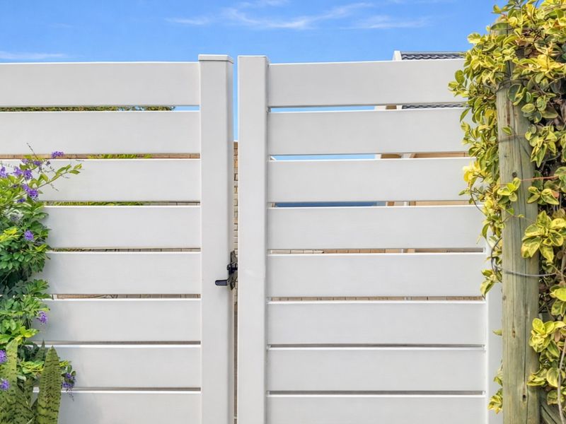 A modern white horizontal slat pedestrian gate providing secure access to the property exterior.