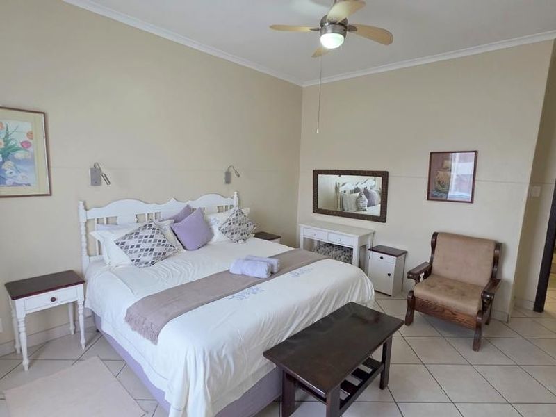 Spacious bedroom featuring tiled flooring, a ceiling fan, and an en-suite bathroom access, offering a comfortable and functional living space.