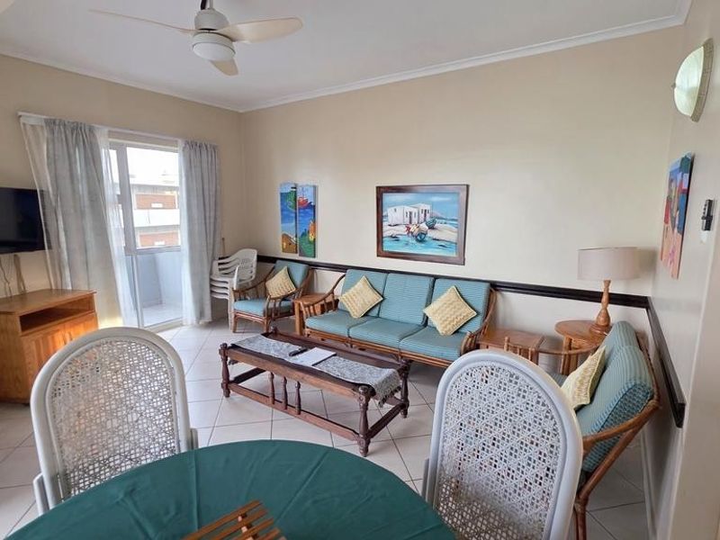 A comfortable living room area featuring tiled flooring, a ceiling fan, and direct access to a balcony through a glass door.
