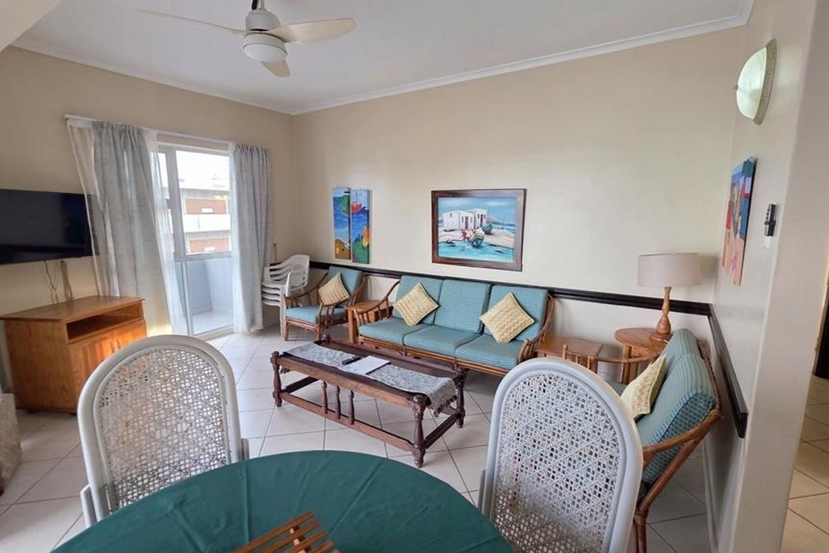 A comfortable living room area featuring tiled flooring, a ceiling fan, and direct access to a balcony through a glass door.