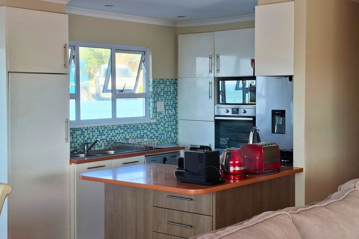 A functional kitchen featuring white cabinetry, a mosaic tile backsplash, built-in oven, and a breakfast bar island with a laminate countertop.