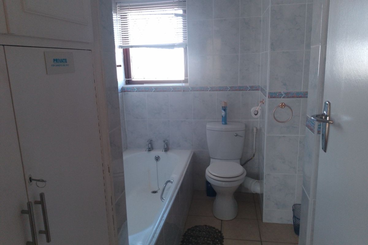 A functional bathroom featuring a built-in bathtub, a standard toilet, and tiled walls with a decorative border.