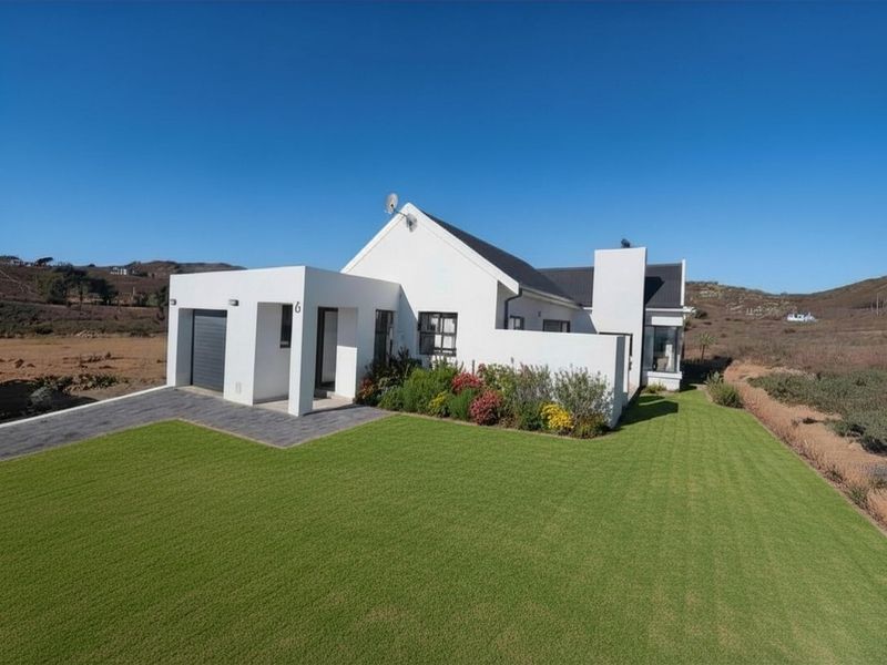 A modern, well-maintained single-story house featuring a clean white facade, attached garage, and a neatly manicured lawn in a quiet, open setting.