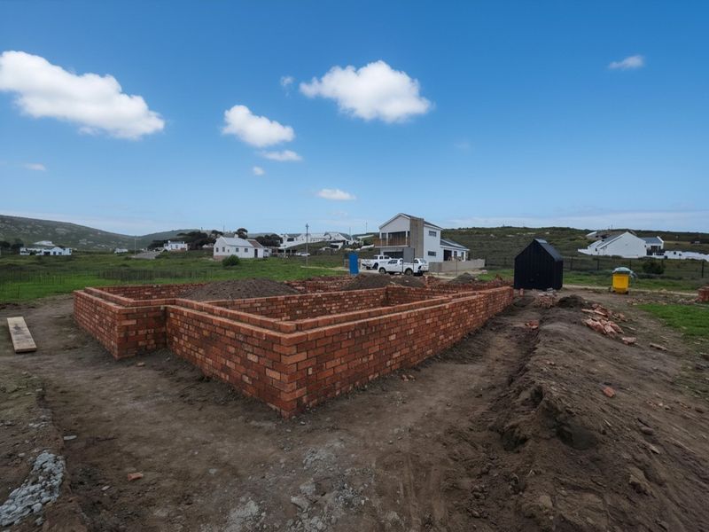 A construction site showing the brick foundation walls of a new house project in a residential area.
