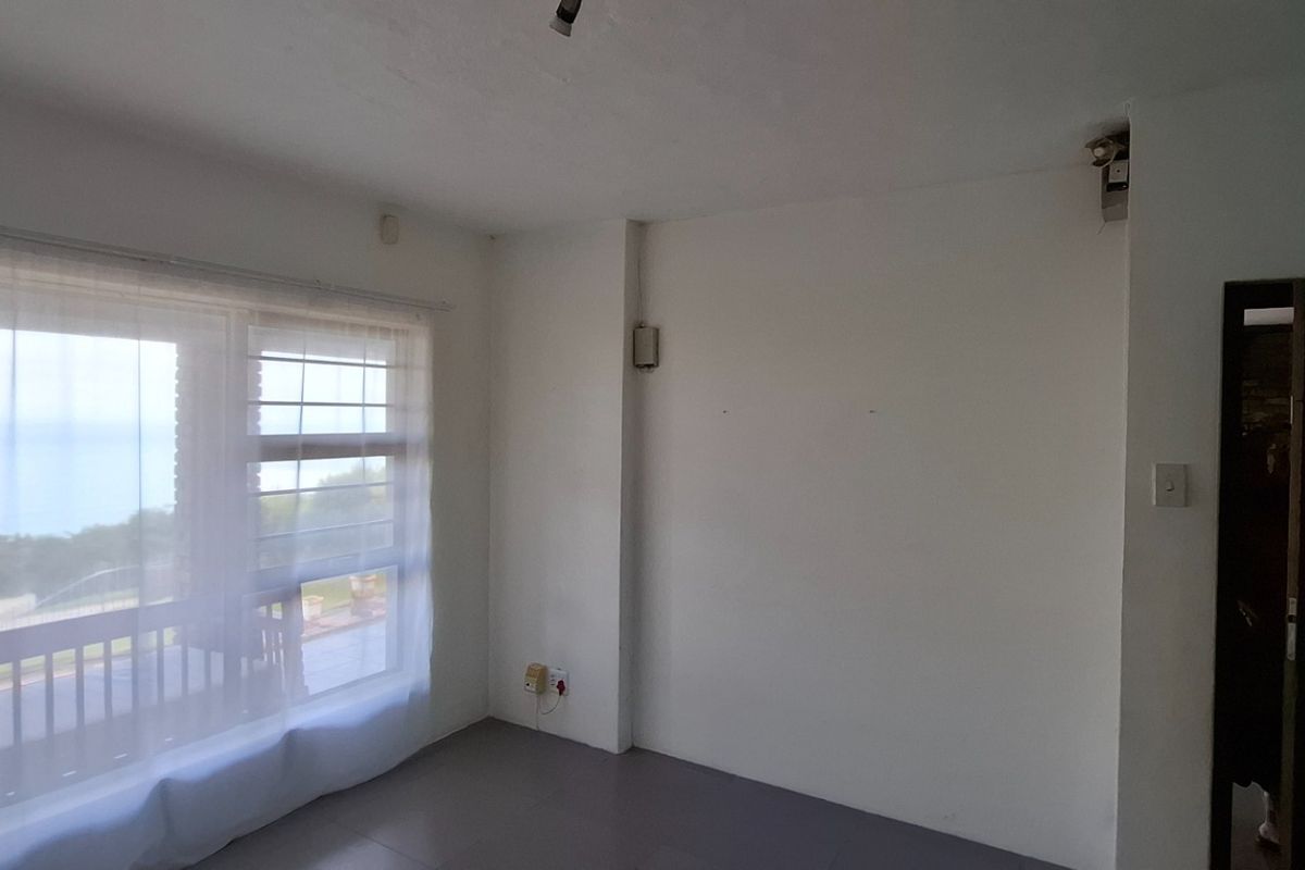 A bright, empty bedroom featuring large windows with natural light, tiled flooring, and direct access to an outdoor balcony area.