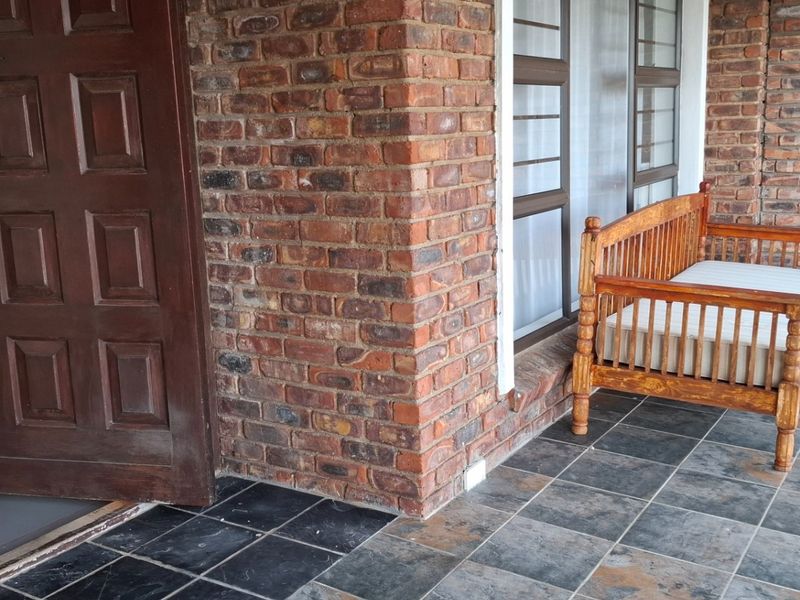 A covered patio area featuring exposed face-brick walls and dark slate-style floor tiles, providing a rustic outdoor transition space.
