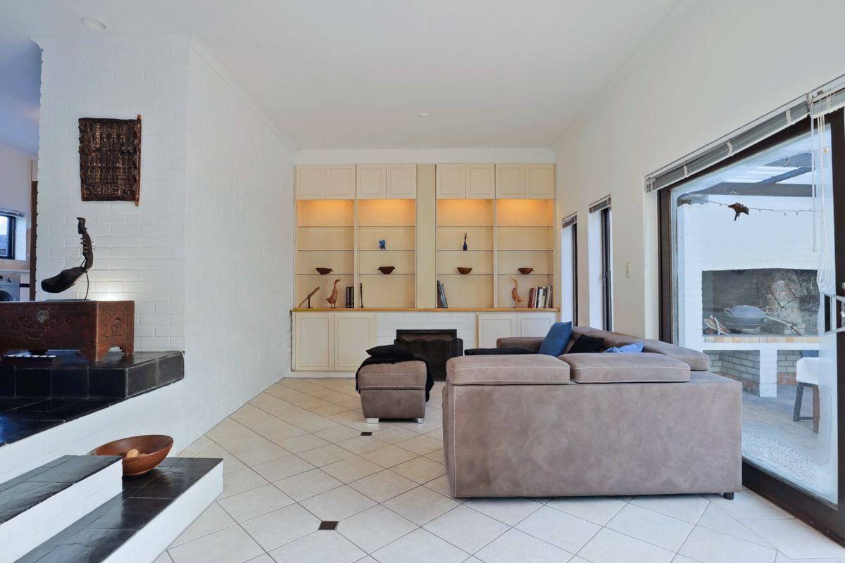 Spacious living room featuring tiled flooring, a built-in fireplace, and custom cabinetry with integrated lighting, opening onto an outdoor patio area.