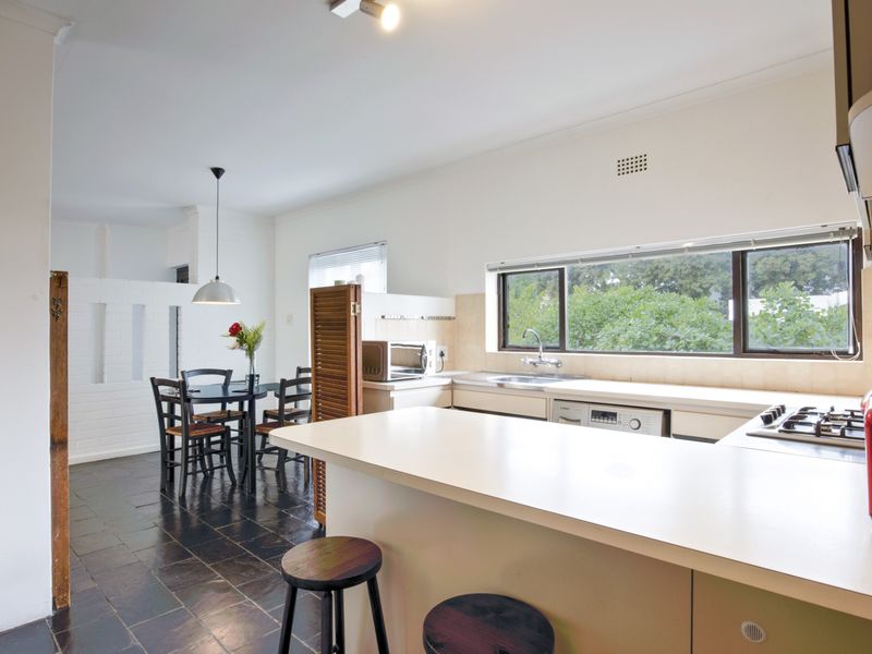 Open-plan kitchen and dining area featuring built-in cabinetry, gas hob, integrated dishwasher, and tiled flooring with a view of the garden.