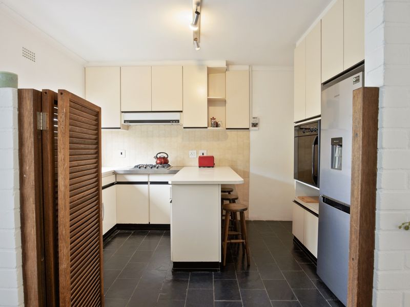Functional kitchen featuring built-in cabinetry, gas cooktop, integrated oven, and a breakfast bar with tiled flooring.