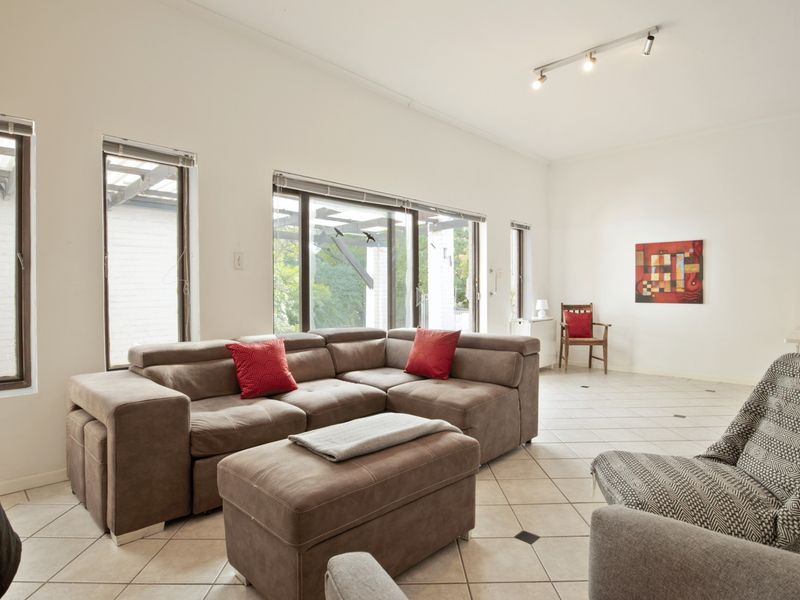 Spacious living room featuring neutral tiled flooring, track lighting, and large sliding glass doors that provide ample natural light and access to the outdoors.