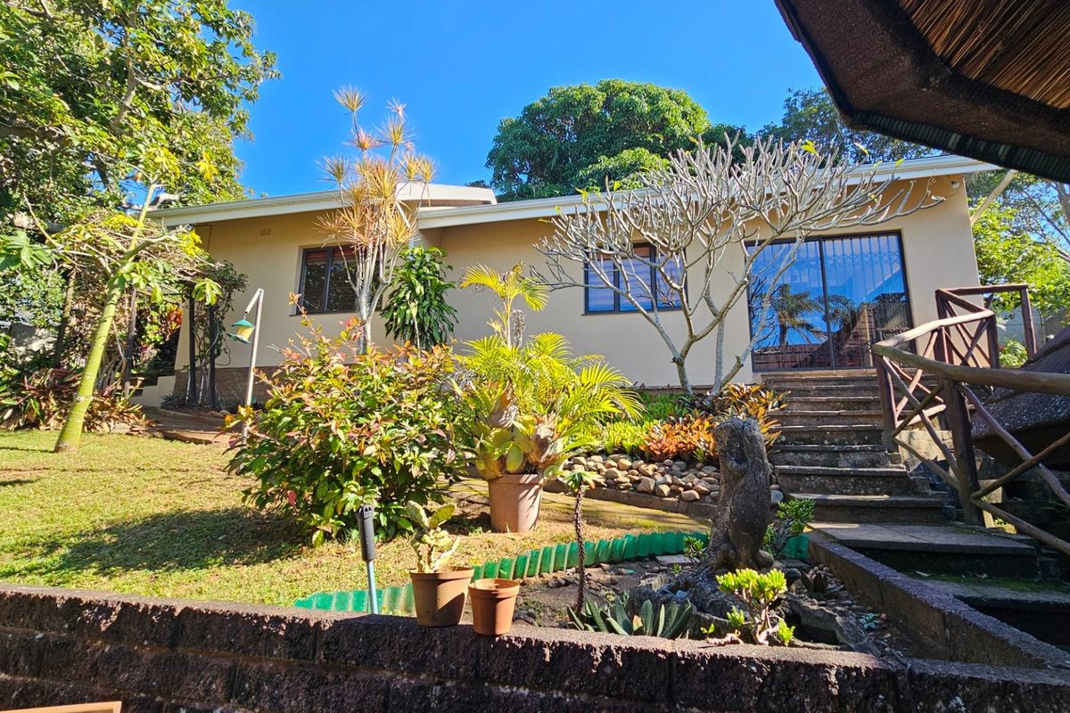 Rear view of the property featuring a landscaped garden, concrete staircase leading to sliding glass doors, and a partial view of a thatched outdoor structure.