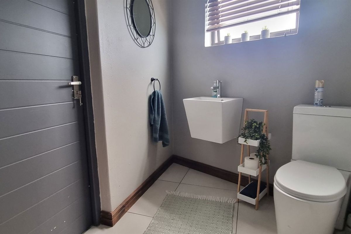 A modern guest bathroom featuring a wall-mounted basin, a sleek toilet, and tiled flooring with neutral wall finishes.