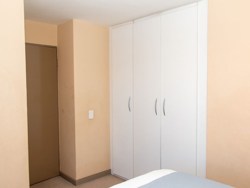 A bedroom featuring built-in white cabinetry with modern handles and a neutral wall finish.