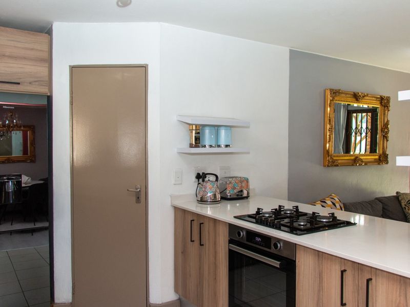 Modern kitchen area featuring a built-in gas hob, integrated oven, and light wood cabinetry with a clean white countertop.
