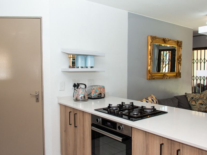 Modern kitchen island featuring a built-in gas hob and oven, complemented by light wood cabinetry and white stone countertops.