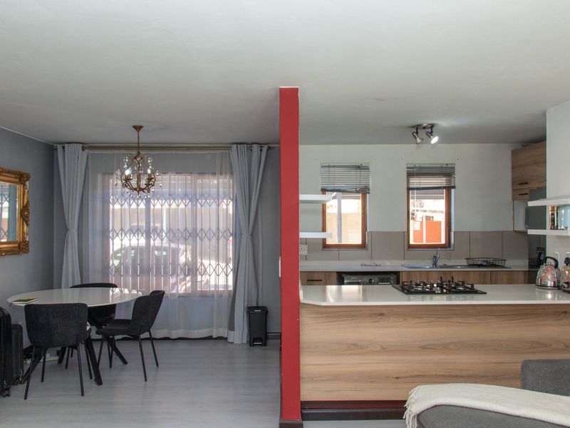 Open-plan living and dining area featuring a modern kitchen with wood-finish cabinetry, stone countertops, and a built-in gas hob.