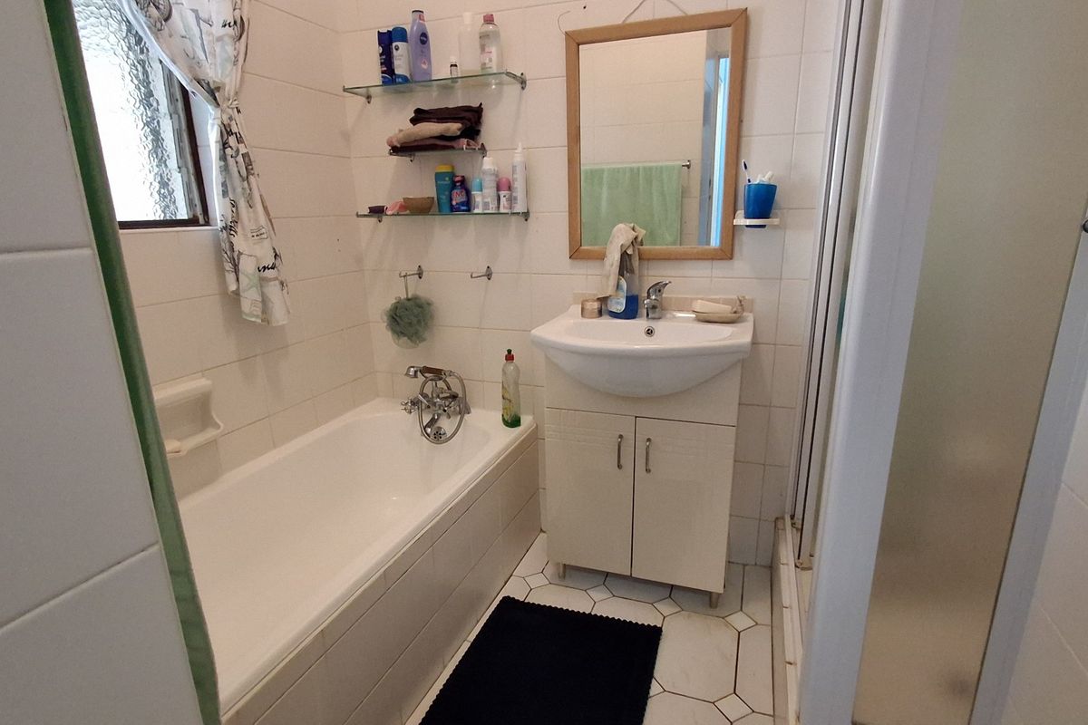 A functional bathroom featuring a bathtub, a pedestal-style vanity with storage, and a separate shower enclosure with tiled walls.