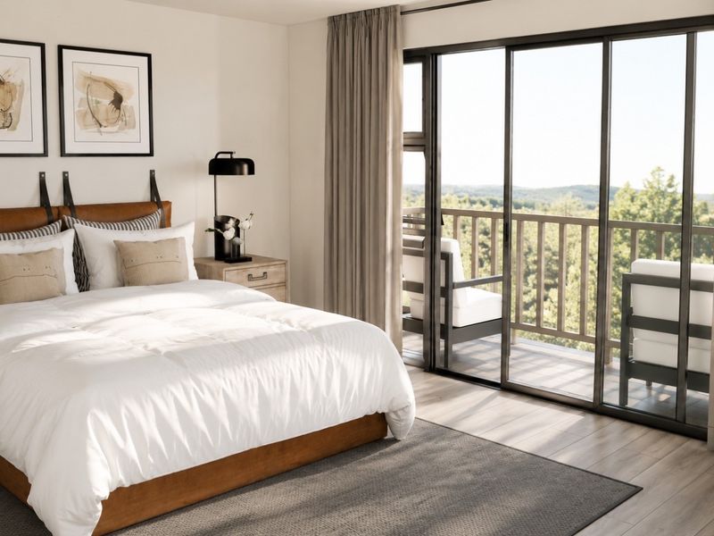 A well-appointed bedroom featuring modern laminate flooring and large sliding glass doors that open onto a private balcony with scenic views.