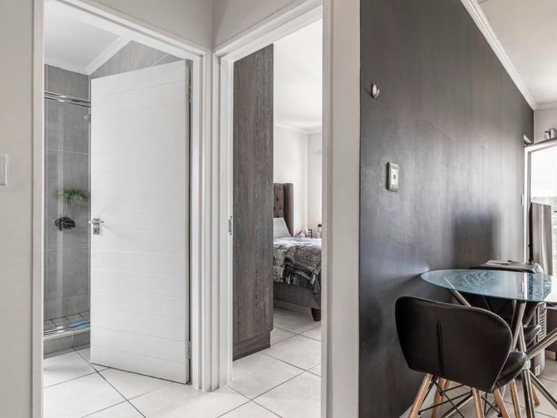 A view from the hallway looking into a bathroom and bedroom, featuring tiled flooring and modern interior finishes.