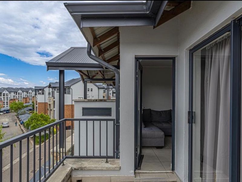 A covered balcony featuring tiled flooring, a metal balustrade, and direct access to the interior living space via a sliding glass door.
