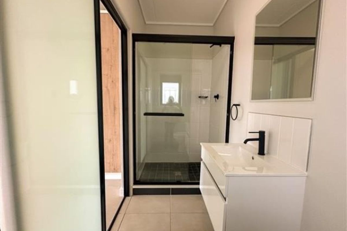 Modern bathroom featuring a sleek vanity with a black faucet, a glass-enclosed shower, and contemporary tile flooring.