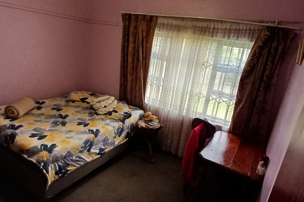 A bedroom featuring a built-in wardrobe and a window fitted with a security gate, offering a functional space with potential for cosmetic updates.