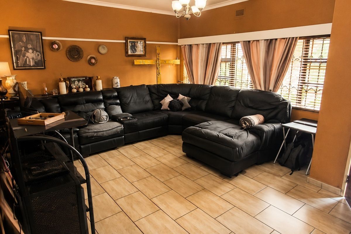 A living room featuring ceramic tile flooring, a ceiling light fixture, and access to an exterior door.