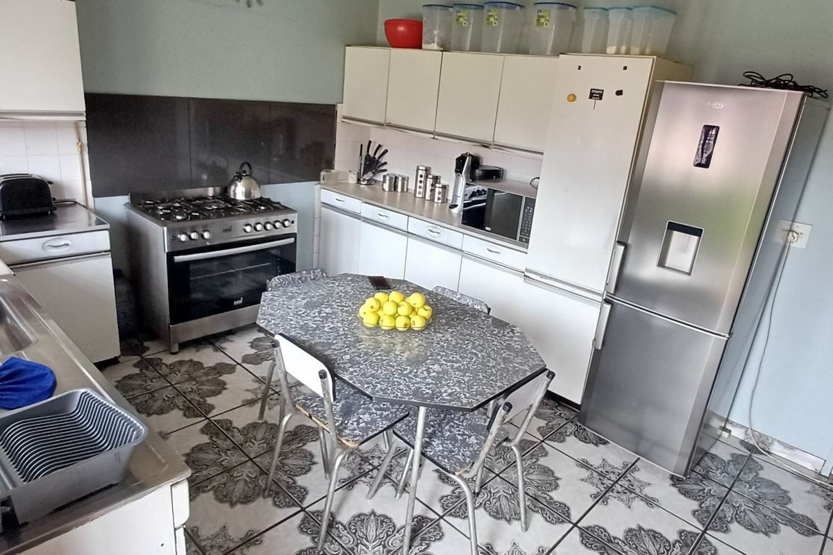 Functional kitchen featuring gas stove, oven, stainless steel sink, and ample built-in cabinetry with patterned tiled flooring.