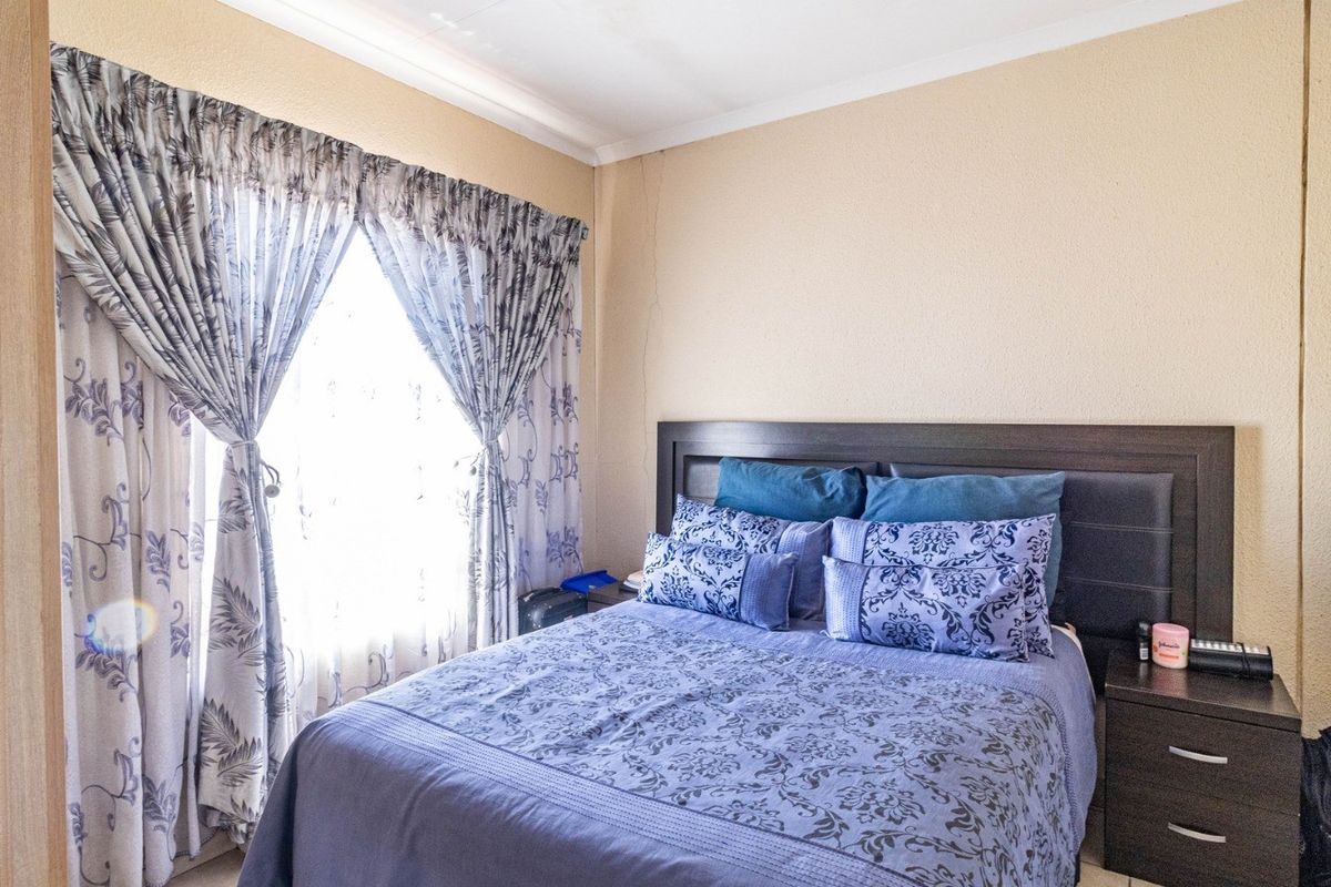 A bedroom featuring a built-in wardrobe and a window with curtains.