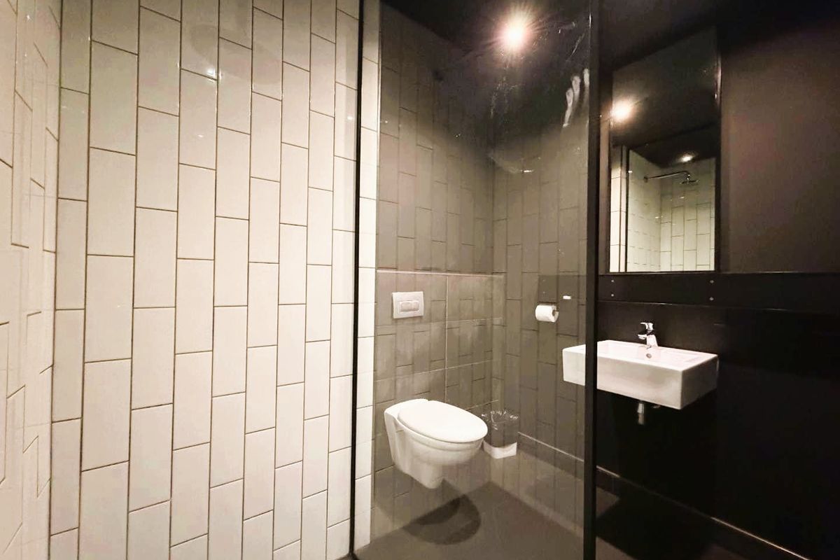 Modern bathroom featuring a wall-mounted toilet, floating vanity sink, and a glass-enclosed shower with contrasting white and dark grey subway tiling.