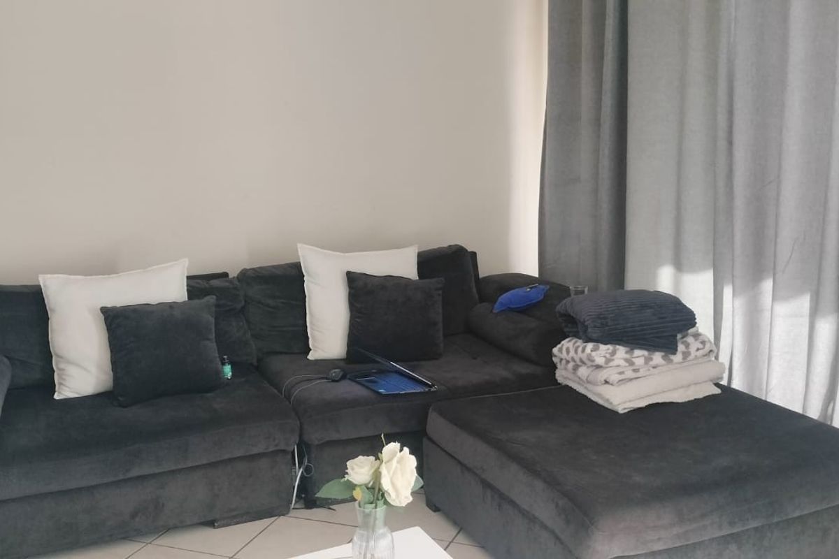 A living room area featuring tiled flooring and floor-to-ceiling curtains.