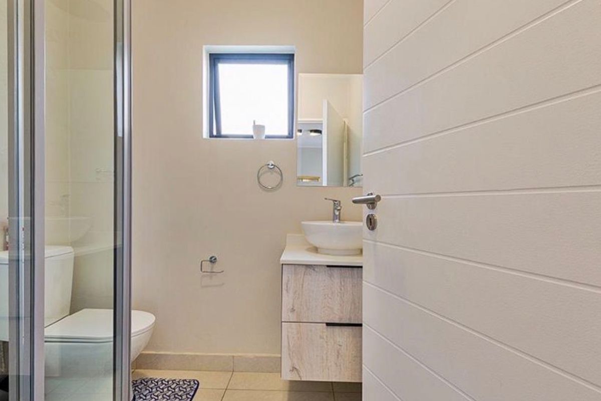 A modern bathroom featuring a glass-enclosed shower, a contemporary vanity with a vessel sink, and neutral floor tiling.