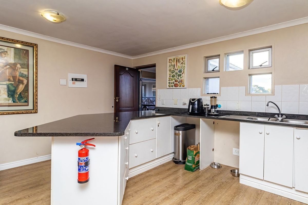 Functional kitchen featuring a breakfast bar, dark granite countertops, white cabinetry, and a tiled splashback, providing a practical layout for daily meal preparation.