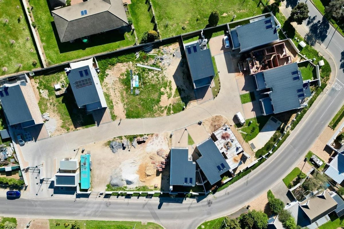 Aerial view of a townhouse development site showing multiple units, paved access roads, and ongoing construction progress.