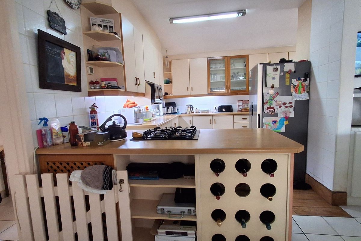 A functional kitchen featuring a central island with a built-in gas hob, integrated wine rack, and ample cabinetry for storage.