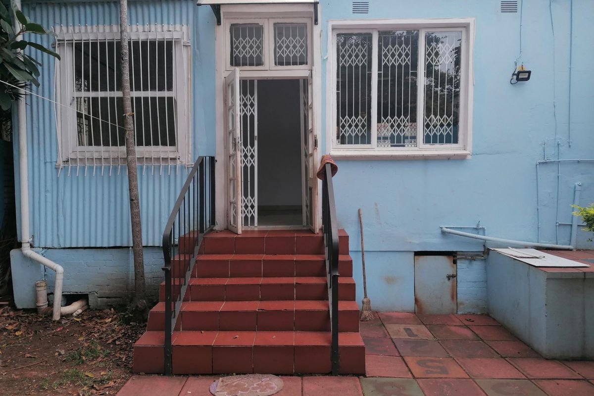 Rear exterior view of the property featuring a tiled staircase, security gates, and corrugated metal wall cladding.