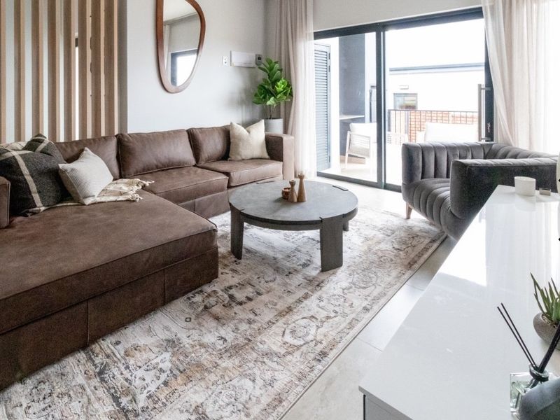 Modern living room featuring tiled flooring, a timber slat room divider, and large sliding glass doors providing access to the patio.
