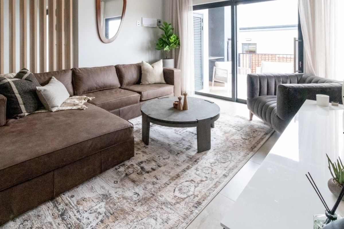 Modern living room featuring tiled flooring, a timber slat room divider, and large sliding glass doors providing access to the patio.
