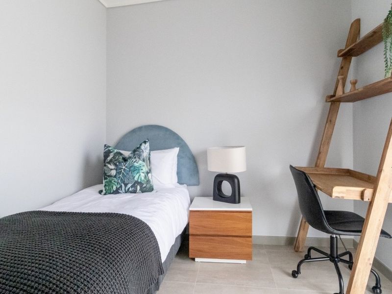 A well-maintained bedroom featuring neutral wall tones and tiled flooring, providing a clean and functional living space.