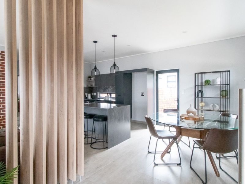 Modern open-plan living and kitchen area featuring a sleek kitchen island, contemporary cabinetry, and a stylish timber slat room divider.