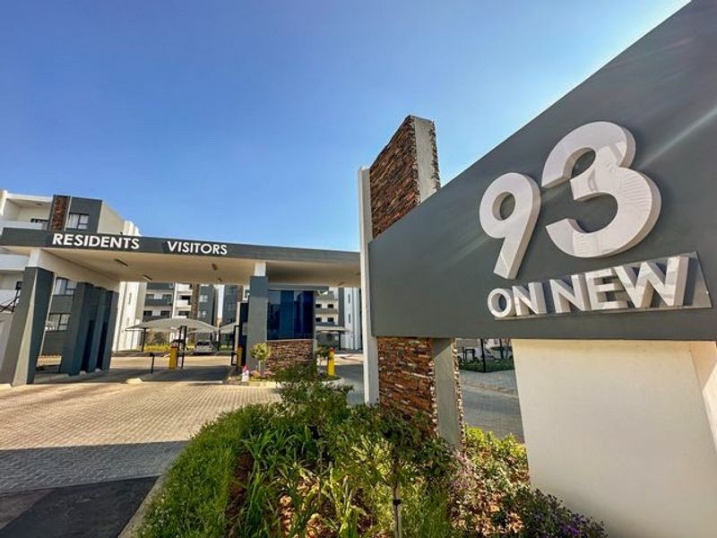 The main entrance and security gatehouse of the 93 on New apartment complex, featuring modern signage and paved access for residents and visitors.