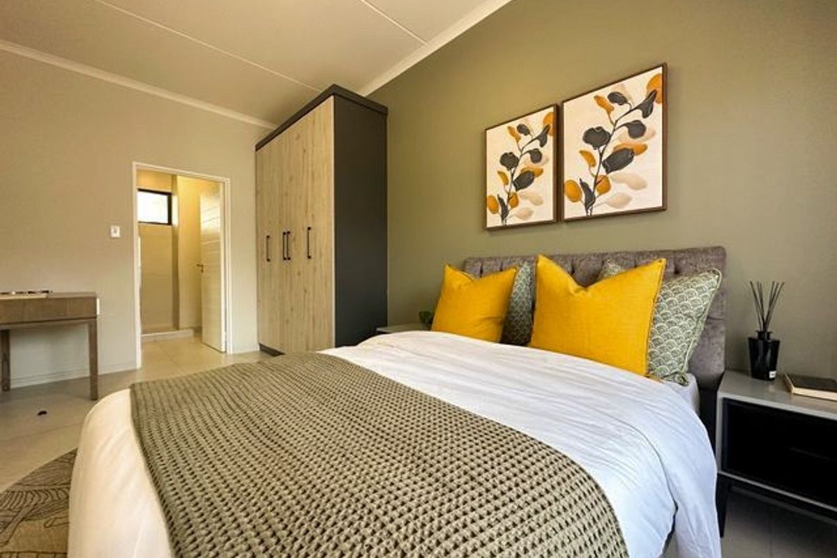 A well-maintained bedroom featuring a built-in wardrobe, neutral wall tones, and tiled flooring, with an adjoining doorway leading to an en-suite area.